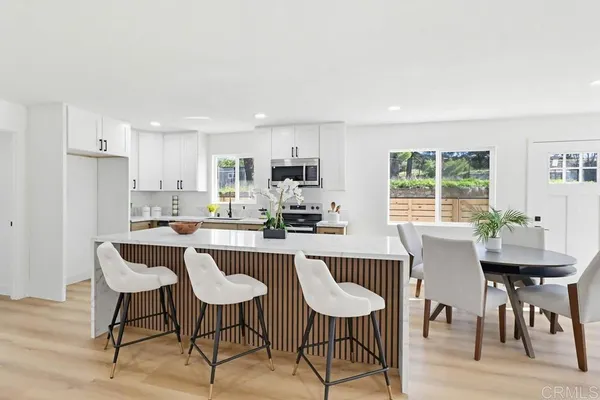 a kitchen with stainless steel appliances granite countertop a dining table chairs and a refrigerator