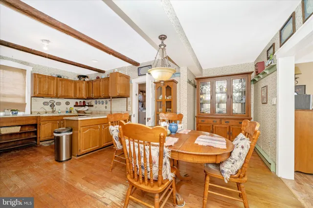 a dining room with wooden floor a chandelier a wooden table and chairs
