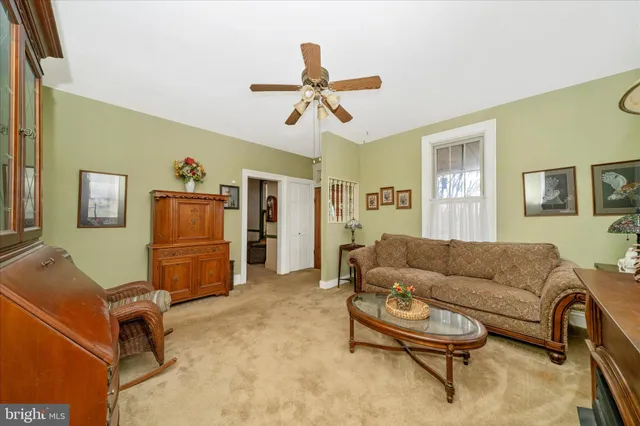 a living room with furniture a chandelier fan and a window