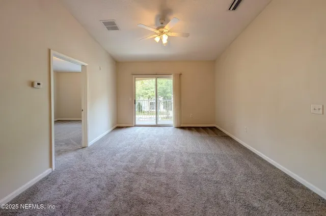 a view of empty room with a ceiling fan and window