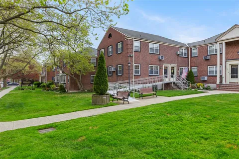 a front view of a building with a garden and plants