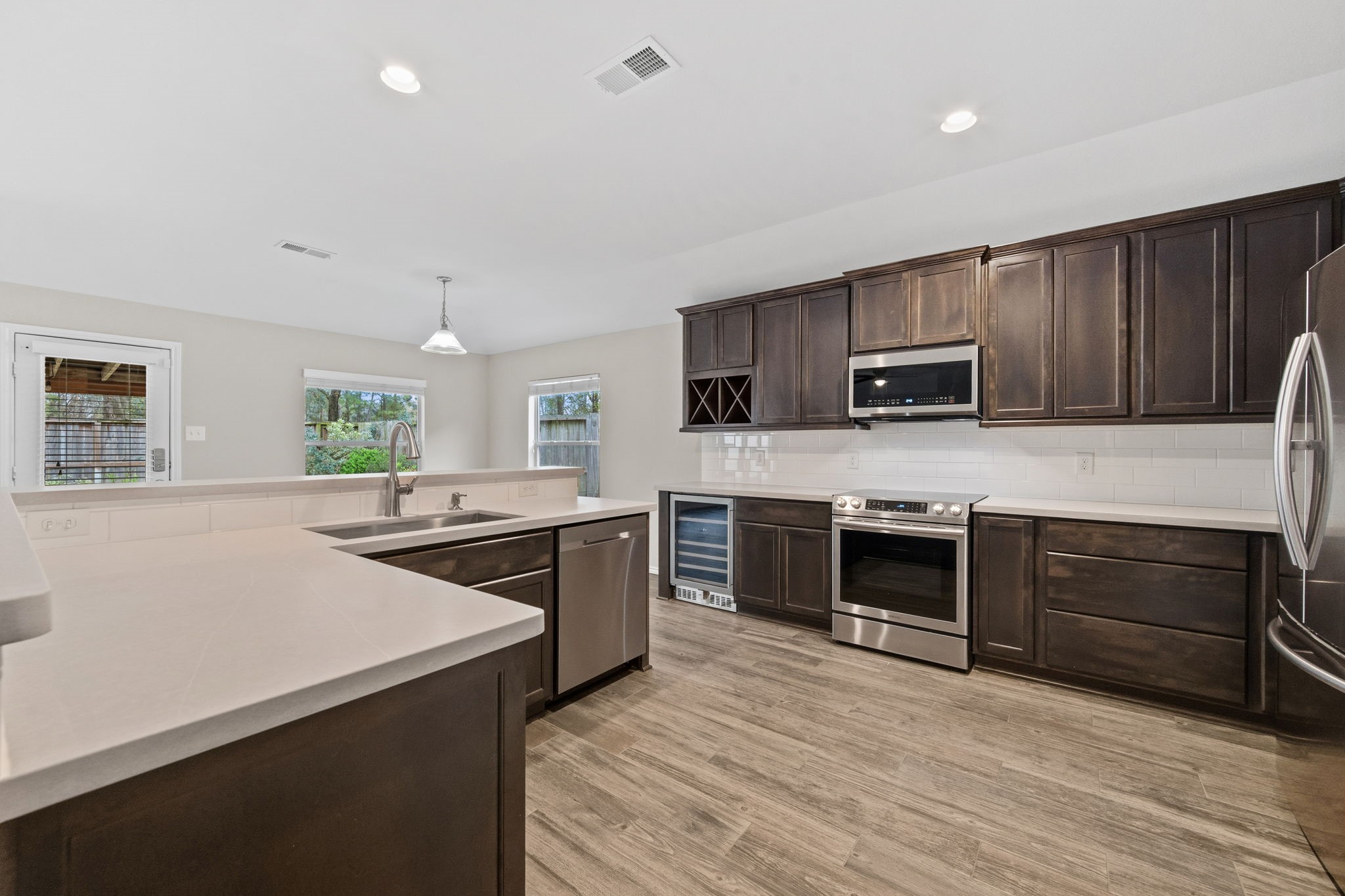 1910 Katlyn Lane Spring, TX 77386 - Photo 13 of 35 This modern kitchen features sleek dark wood cabinets, stainless steel appliances, and a spacious layout with ample counter space. The open design is complemented by light-colored flooring and large windows, providing a bright and inviting atmosphere.