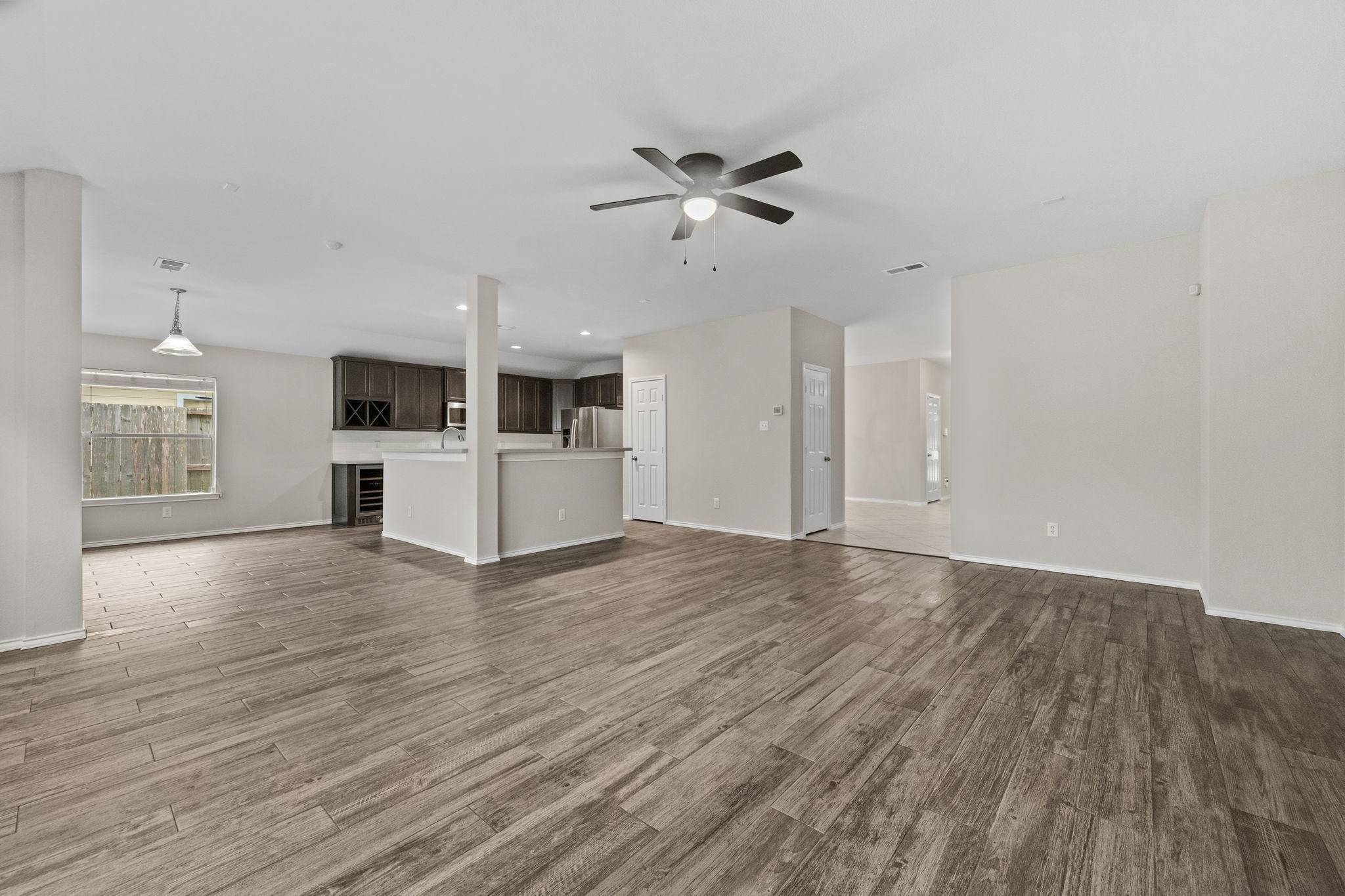 1910 Katlyn Lane Spring, TX 77386 - Photo 8 of 35 This spacious open-concept living area features modern wood-look tile flooring, neutral walls, and ample natural light. The kitchen has newer cabinetry, a breakfast bar, and Samsung stainless steel appliances. A ceiling fan and recessed lighting enhance the contemporary feel, making it perfect for entertaining.