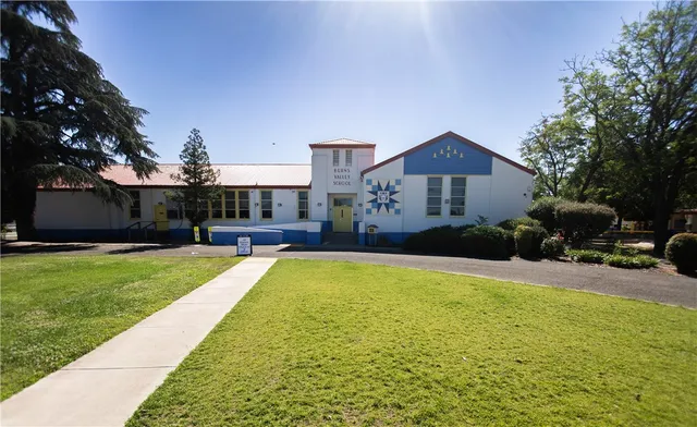 a view of a swimming pool with a yard and large trees