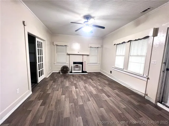 a view of empty room with wooden floor and fan