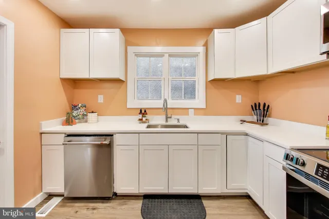 a kitchen with white cabinets appliances and sink