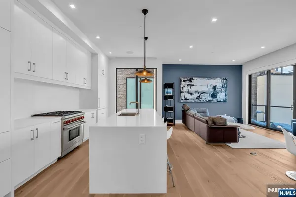 a kitchen with stainless steel appliances granite countertop a refrigerator a stove oven a sink dishwasher and white cabinets with wooden floor