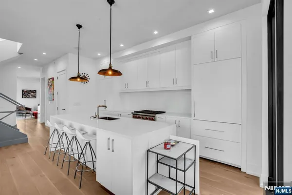 a kitchen with stainless steel appliances granite countertop a sink a stove a refrigerator and white cabinets with wooden floor