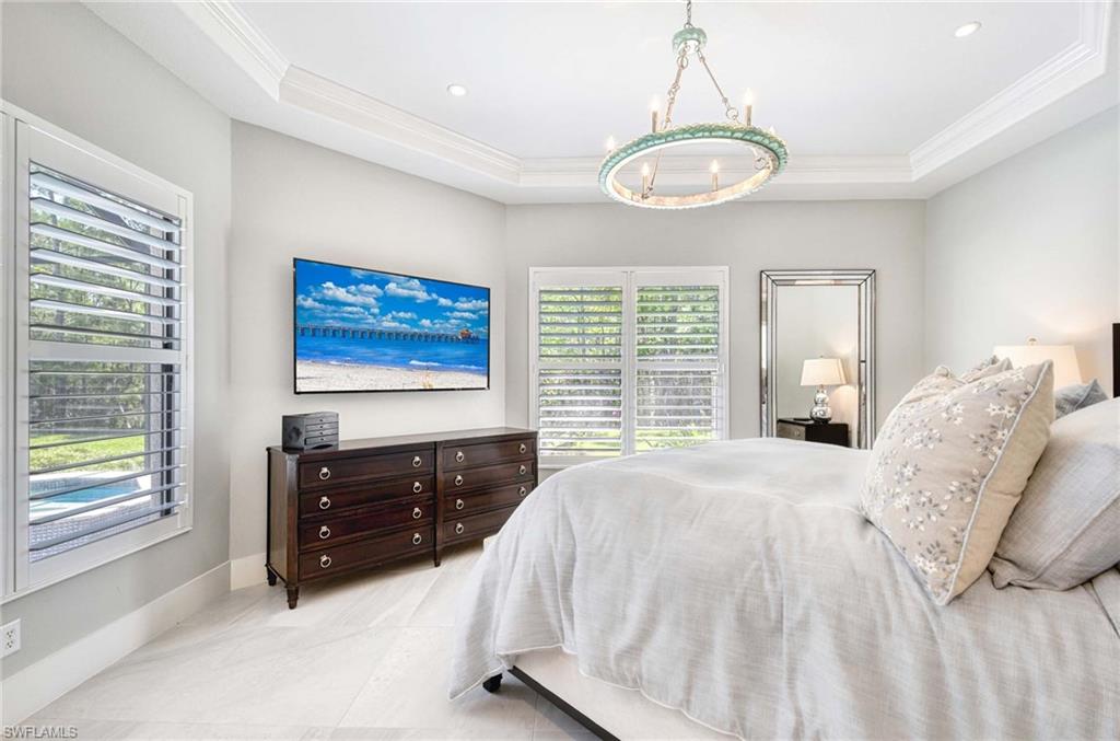 7516 Treeline Drive Naples, FL 34119 - Photo 12 of 33 a spacious bedroom with a bed and a chandelier