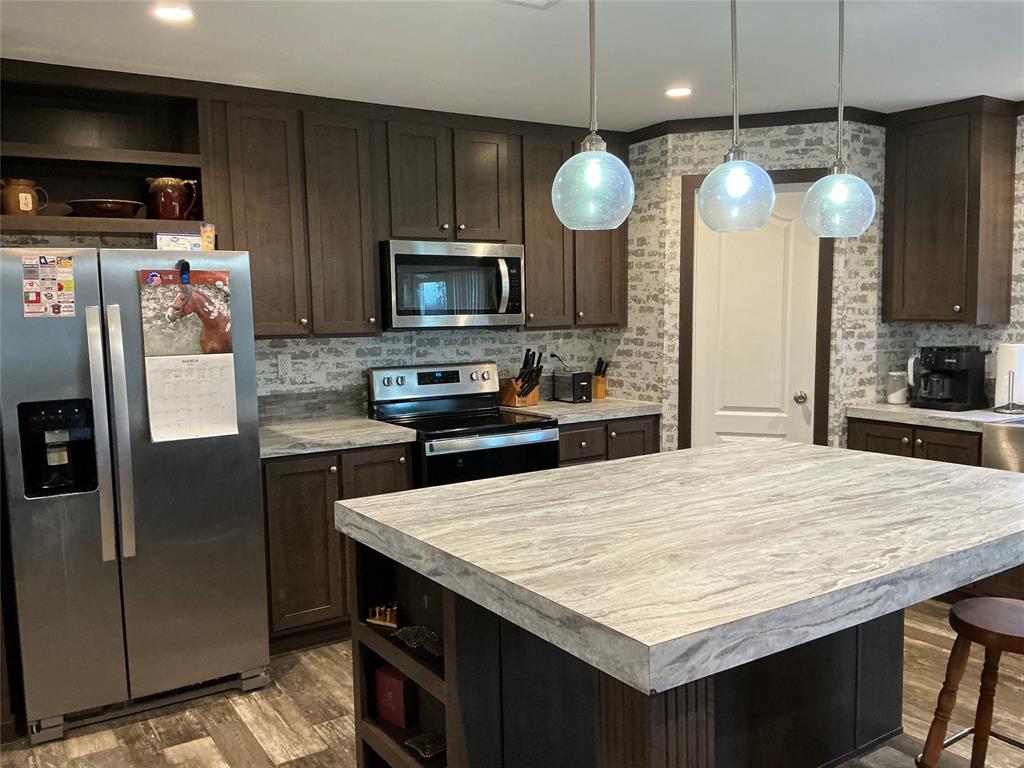 1595 Cr 131 Rising Star Tx 76471 Rising Star, TX 76471 - Photo 18 of 20 a kitchen with stainless steel appliances a kitchen island a refrigerator wooden cabinets and a sink