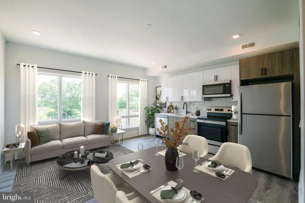 a living room with furniture a refrigerator dining table and kitchen view