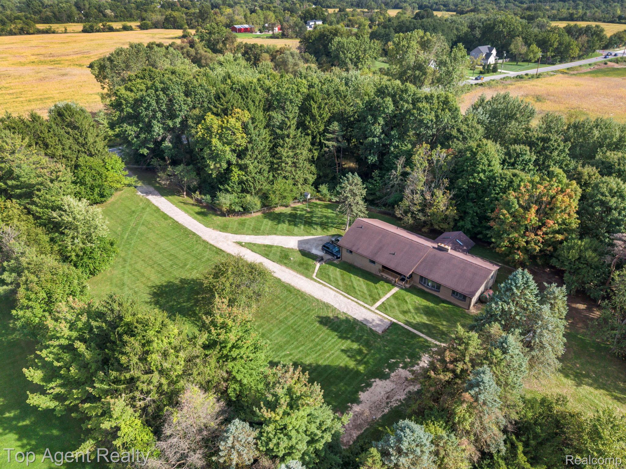 8269 Currie Road Northville, MI 48168 - Photo 65 of 80 Expansive lot featuring mature trees, a gravel driveway, and a single-story residence with a brown roof