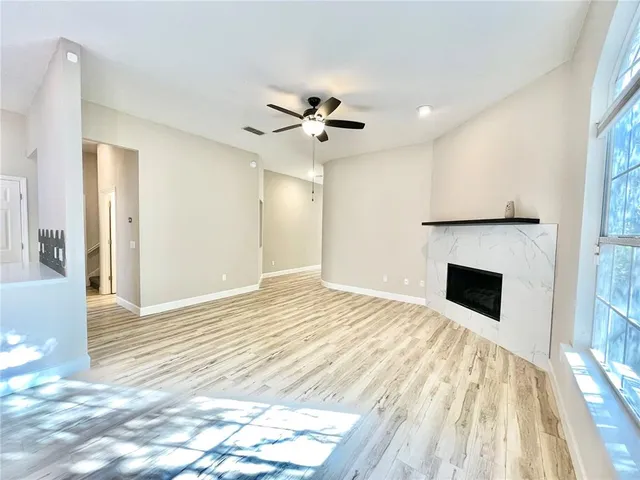 a view of a big room with wooden floor and a chandelier fan