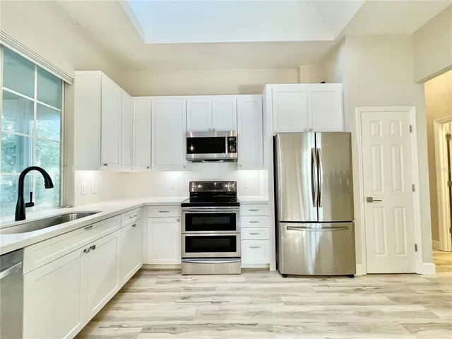 a kitchen with a refrigerator cabinets and wooden floor