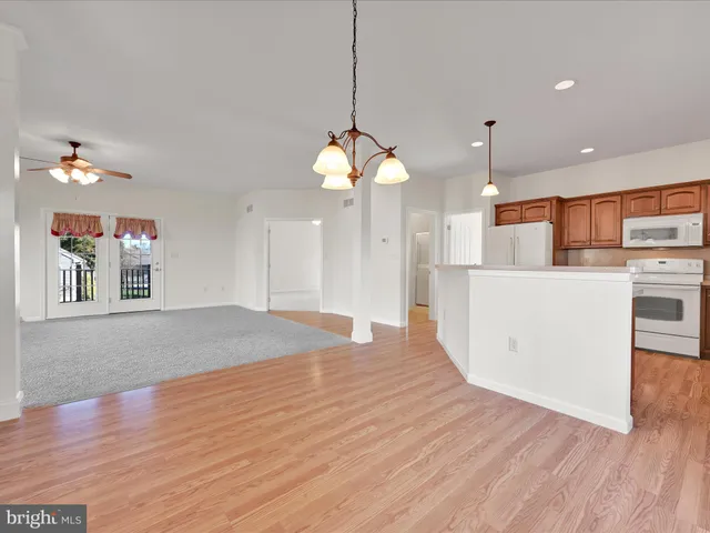 a large kitchen with cabinets wooden floor and a chandelier