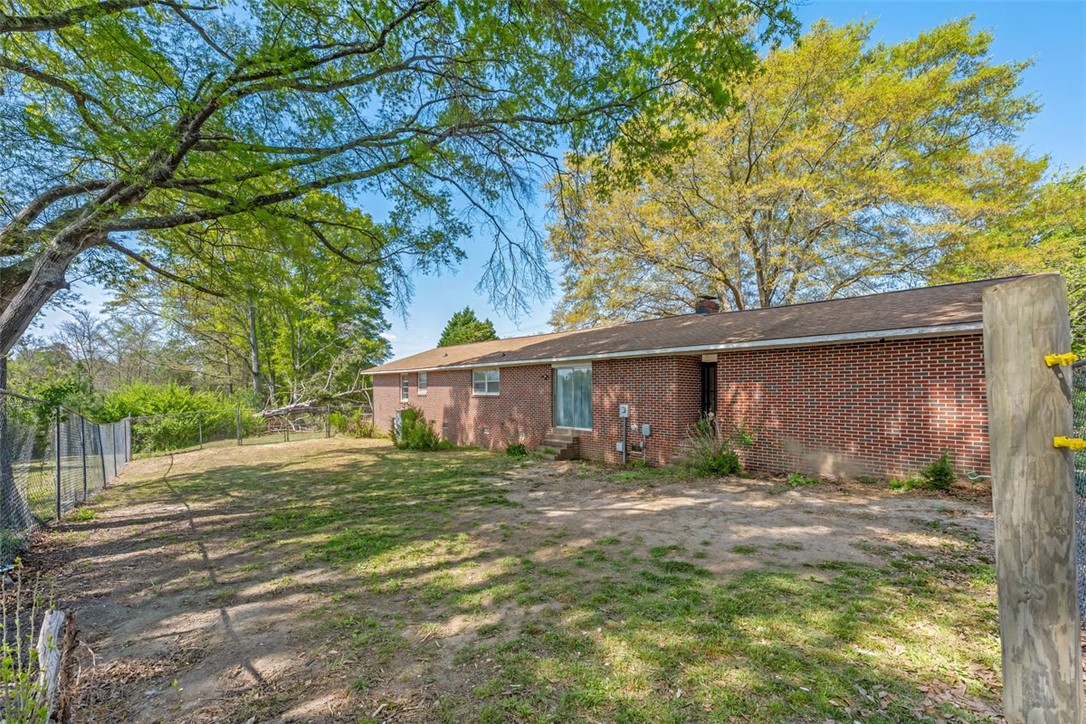 606 County Rd S-1-149 Donalds, SC 29638 - Photo 34 of 38 This ranch-style home features a spacious backyard with mature trees and a chain-link fence.