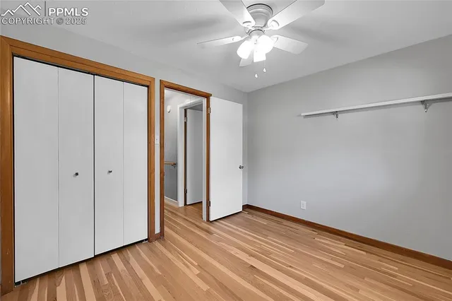 a view of empty room with wooden floor and fan
