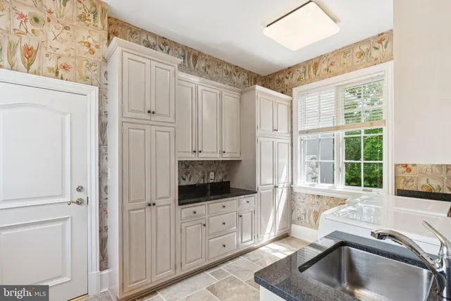 a kitchen with white cabinets and window