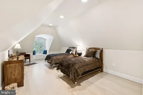 a spacious bedroom with a bed a couch and a potted plant on the dresser