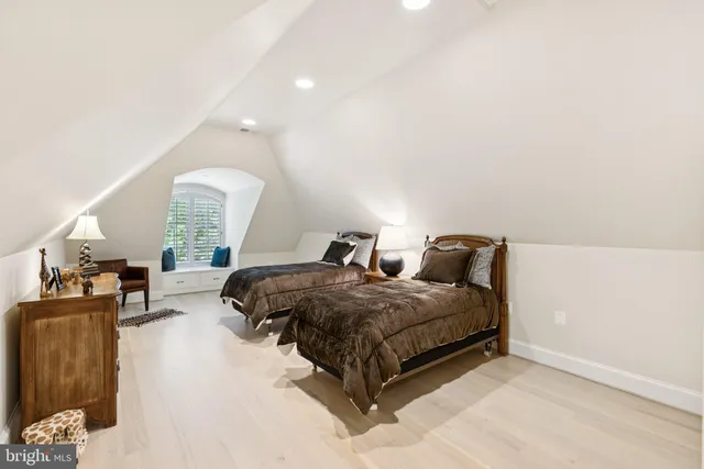 a spacious bedroom with a bed a couch and a potted plant on the dresser