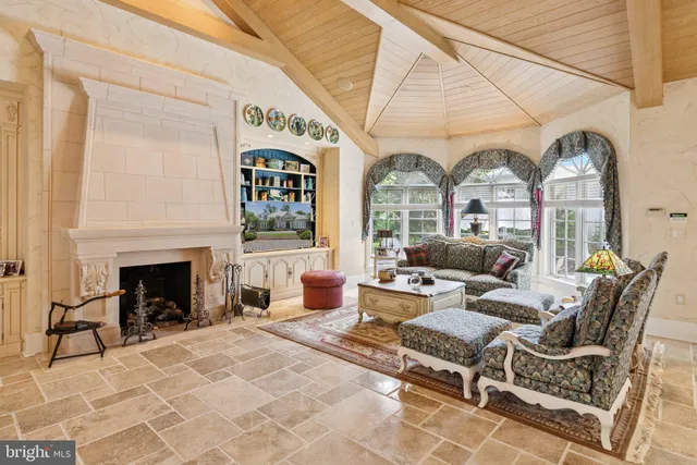a living room with furniture a fireplace and floor to ceiling windows