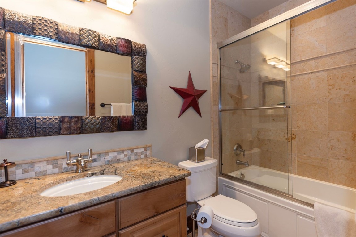 1330 Golden Eagle Road Silverthorne, CO 80498 - Photo 29 of 41 a bathroom with a granite countertop sink toilet mirror and shower