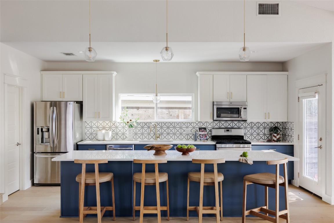 1205 McKinley Avenue Austin, TX 78702 - Photo 10 of 34 a kitchen with stainless steel appliances kitchen island granite countertop a dining table and chairs