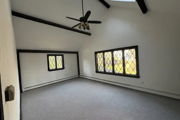an empty room with windows and fan