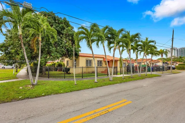 a view of a house with a yard and palm trees