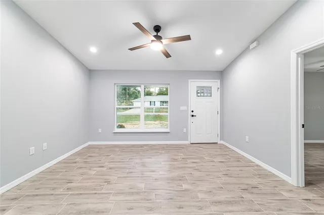a view of an empty room with a window and wooden floor
