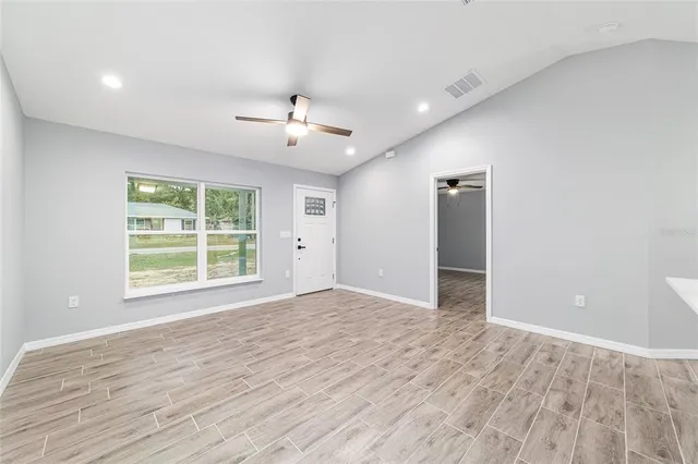 a view of an empty room with window and wooden floor
