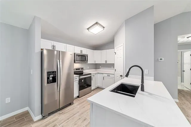 a kitchen with a sink a refrigerator and cabinets