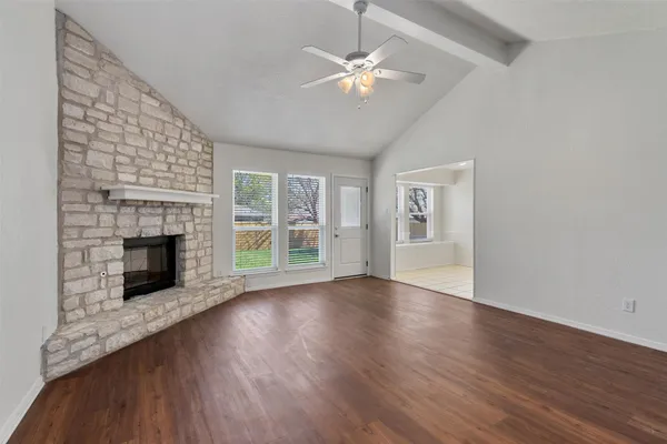 a view of an empty room with wooden floor fireplace and a window