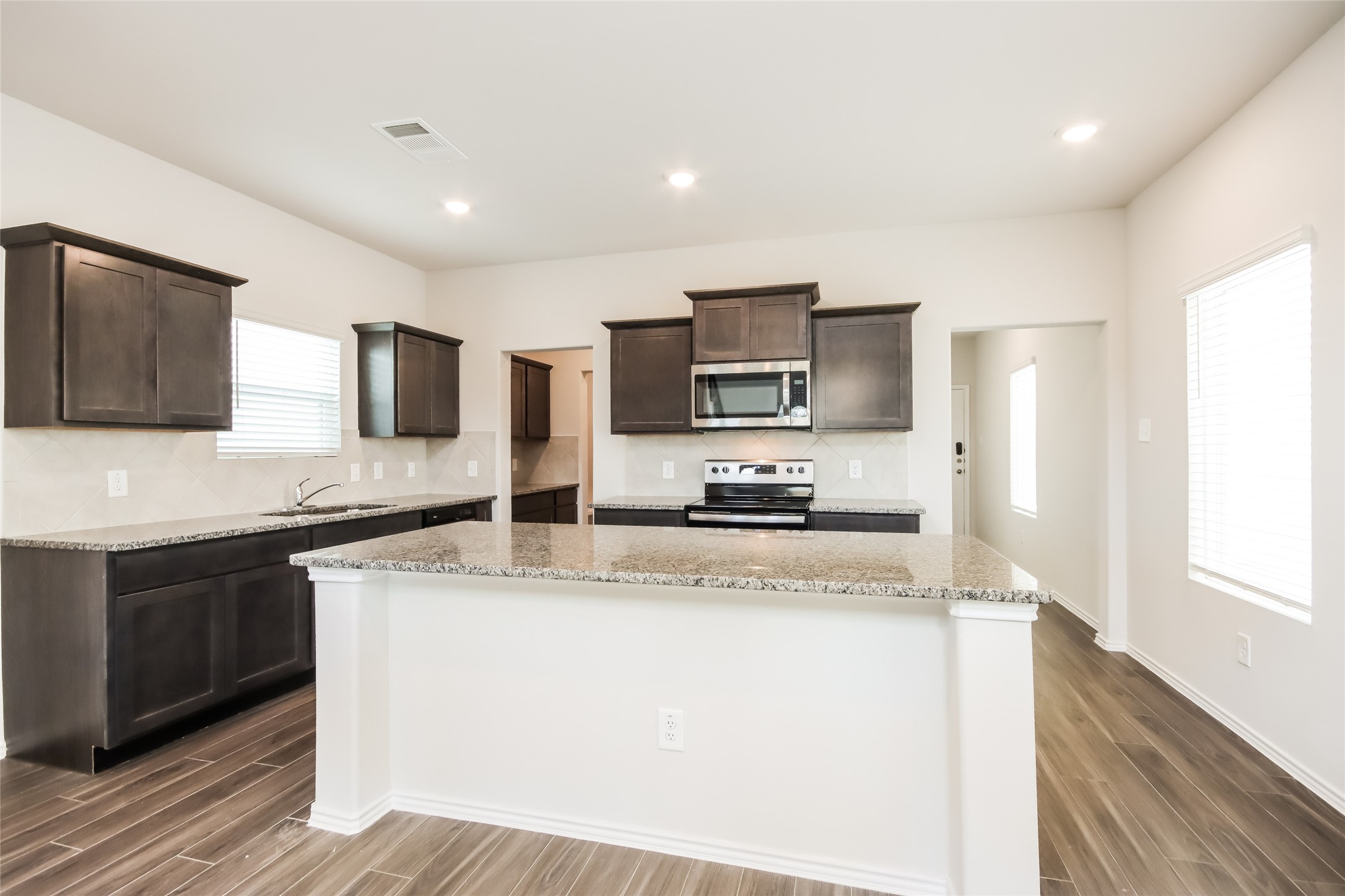 15264 Estrella Road East Houston, TX 77073 - Photo 5 of 14 a kitchen with stainless steel appliances granite countertop a stove a sink a refrigerator a microwave oven with cabinets and wooden floor