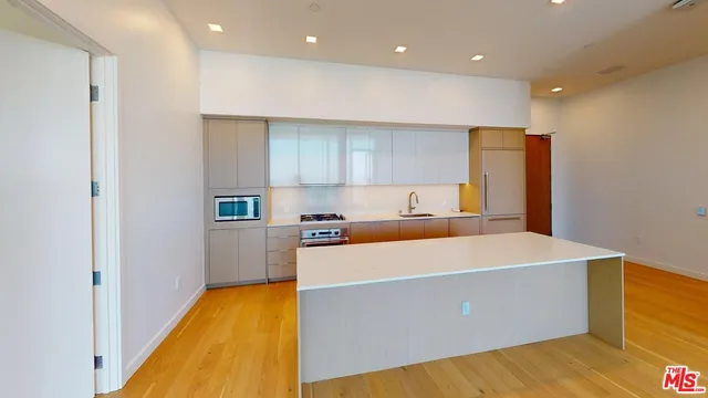 a large kitchen with stainless steel appliances a large counter top a refrigerator and a sink