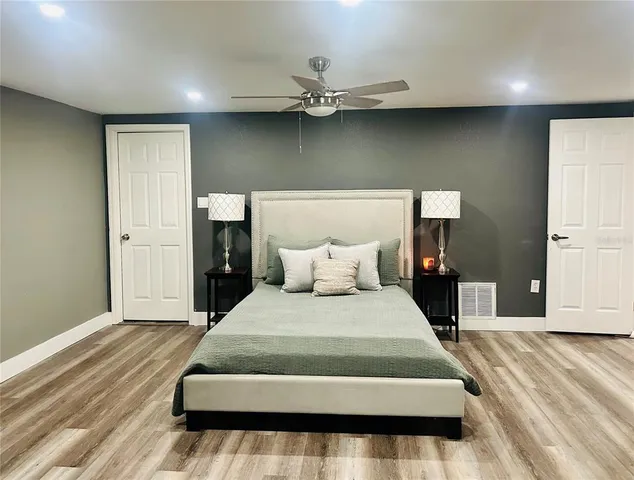 a bedroom with a large bed and wooden floor