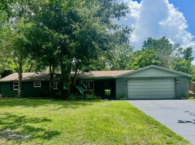 a view of a house with a yard and a large tree