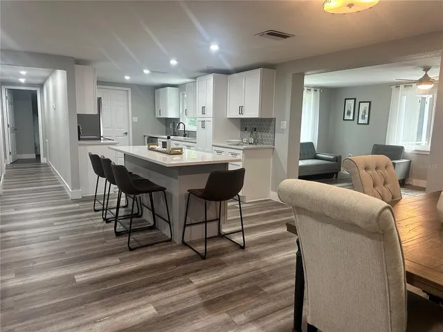 a living room with stainless steel appliances kitchen island granite countertop furniture and wooden floor