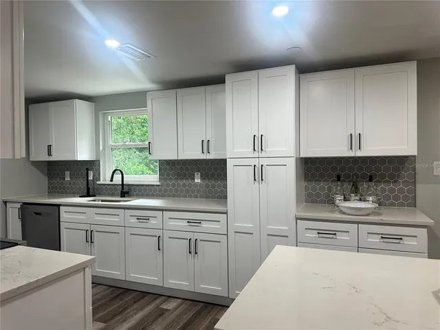 a kitchen with a sink white cabinets and white appliances