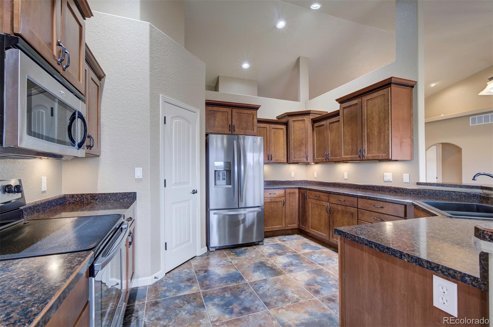 24484 Gale Road Pueblo, CO 81006 - Photo 17 of 43 a kitchen with stainless steel appliances granite countertop a sink refrigerator and cabinets