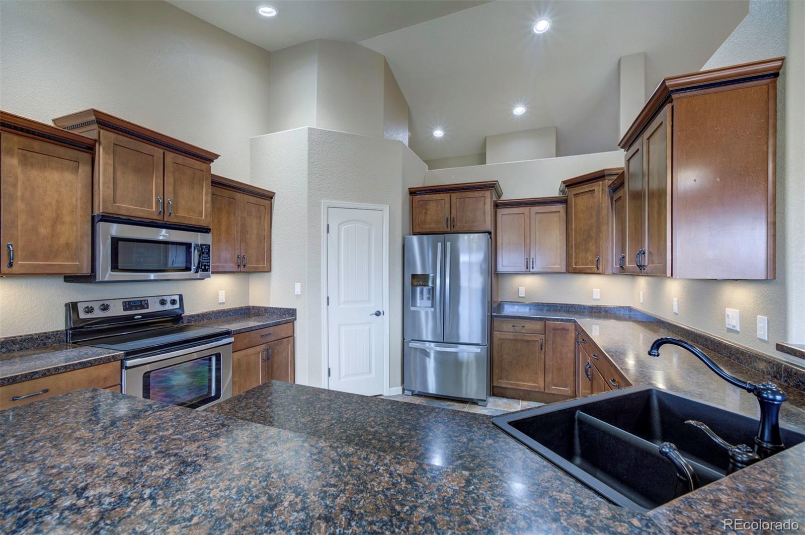 24484 Gale Road Pueblo, CO 81006 - Photo 19 of 43 a kitchen with stainless steel appliances granite countertop a sink a stove and a refrigerator