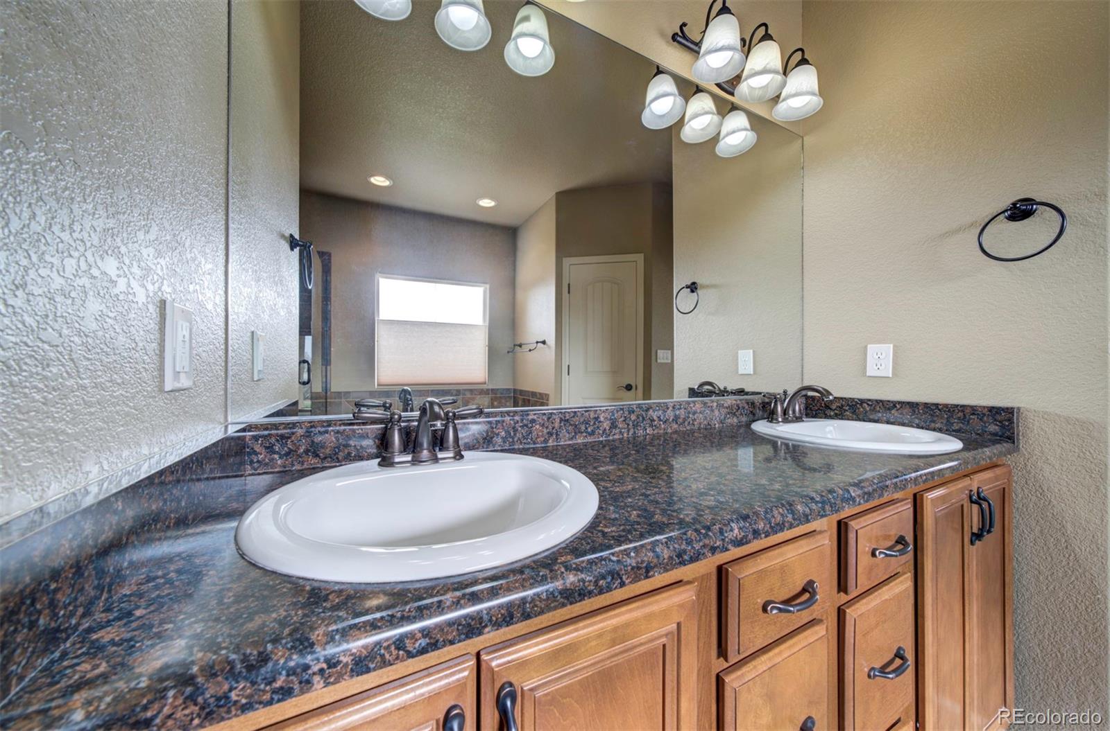 24484 Gale Road Pueblo, CO 81006 - Photo 25 of 43 a bathroom with a granite countertop sink a light fixture and a mirror