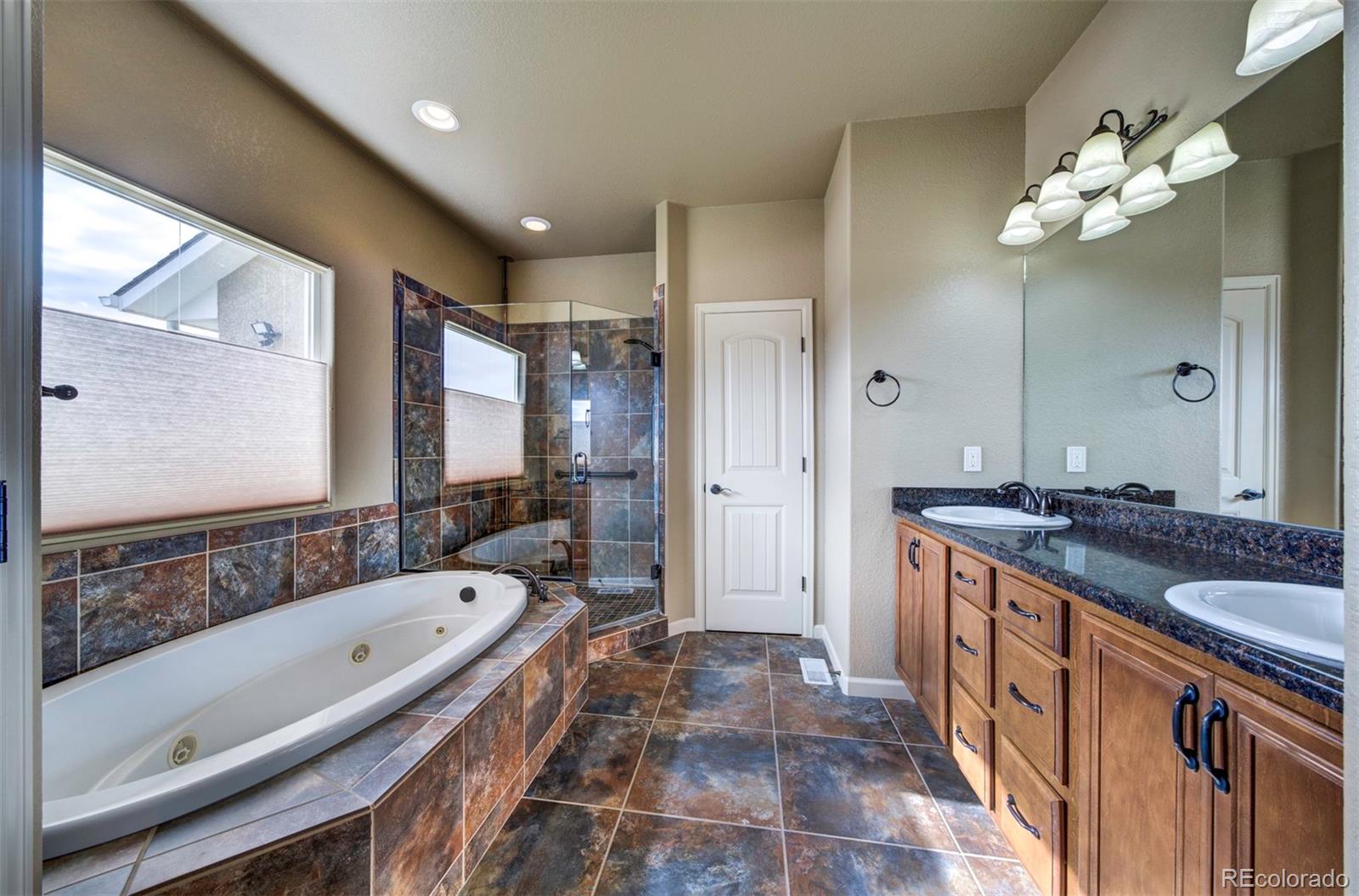 24484 Gale Road Pueblo, CO 81006 - Photo 26 of 43 a spacious bathroom with a granite countertop tub a double vanity sink a vanity and a large mirror