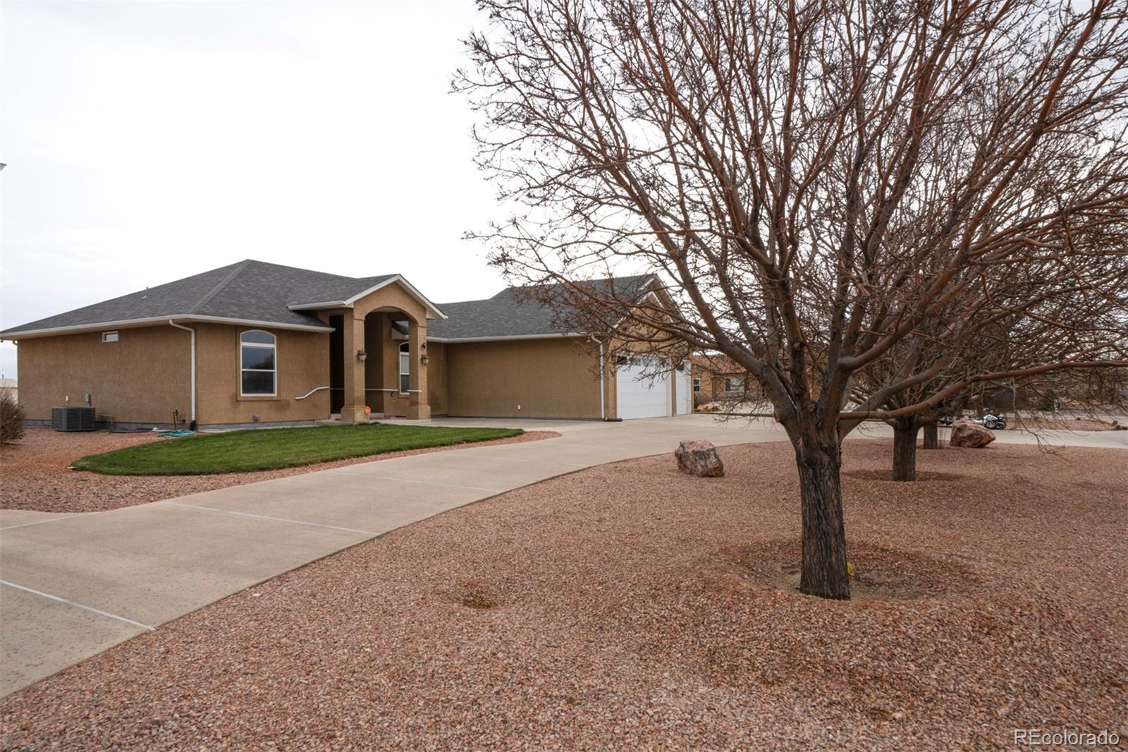 24484 Gale Road Pueblo, CO 81006 - Photo 4 of 43 a front view of a house with a dirt yard and a large tree