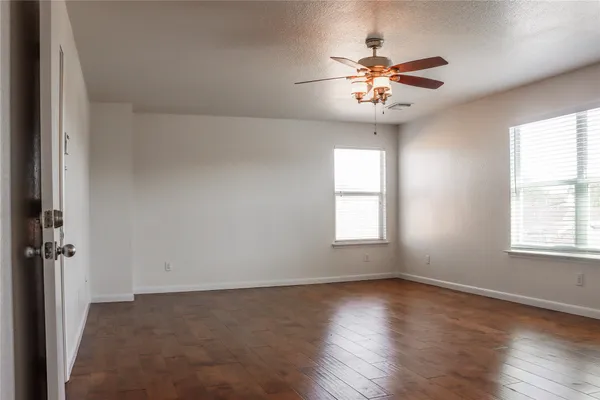 a view of an empty room with window and wooden floor