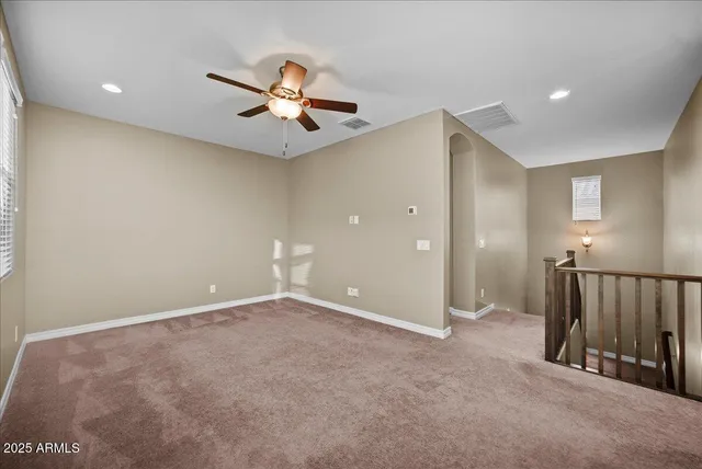 a view of an empty room with window and chandelier fan