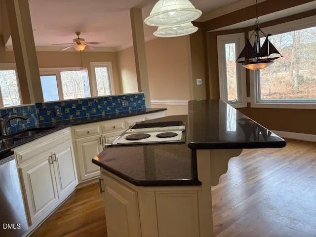 a kitchen with stainless steel appliances granite countertop a refrigerator a stove and white cabinets with wooden floor