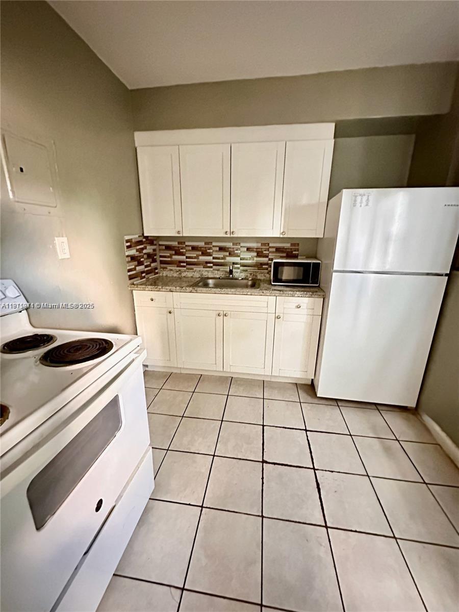 401 Northwest 81st Street Miami, FL 33150 - Photo 5 of 10 a kitchen with a stove a refrigerator and a white cabinets