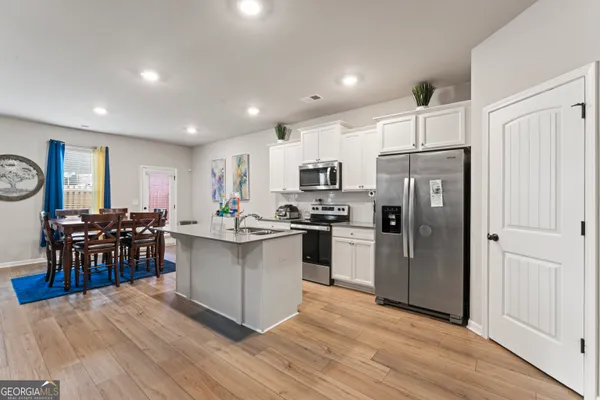 a kitchen with stainless steel appliances a refrigerator a stove a sink a dining table and chairs