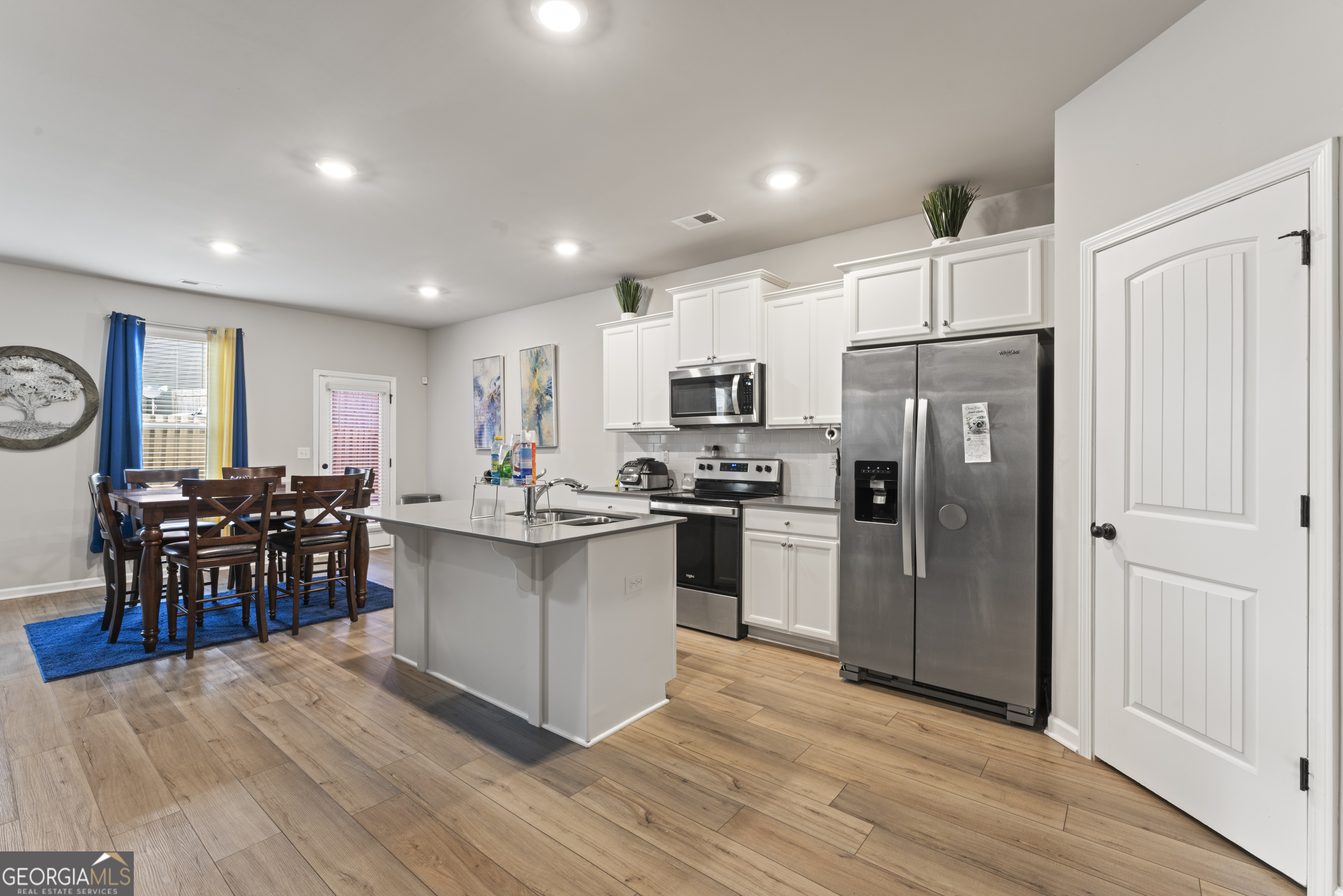 11940 Brightside Parkway Hampton, GA 30228 - Photo 10 of 29 a kitchen with stainless steel appliances a refrigerator a stove a sink a dining table and chairs